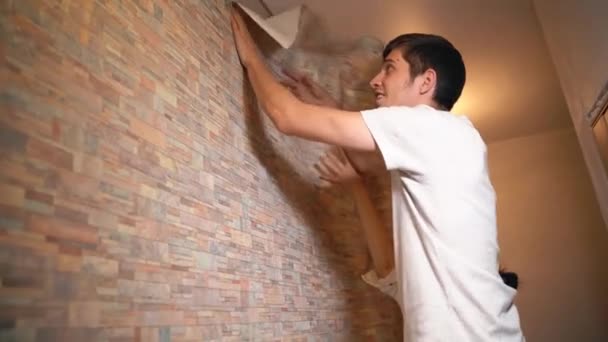 Una pareja casada hace reparaciones en su casa, pegando cuidadosamente el papel pintado — Vídeo de stock