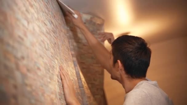 Feliz familia joven haciendo renovaciones en su nuevo apartamento, pegando papel pintado — Vídeos de Stock