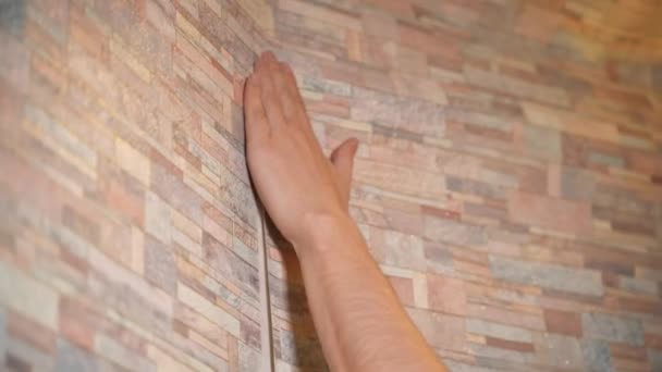 A man makes repairs in his house, neatly gluing wallpaper — Stok video