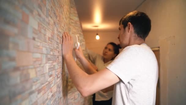 A married couple makes repairs in their house, neatly gluing wallpaper — 图库视频影像