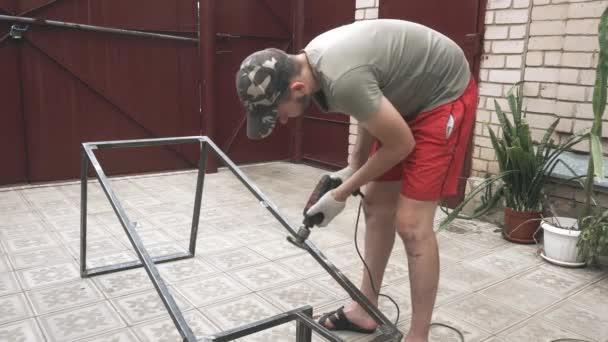 En mand i en arbejdsuniform og handsker med en boremaskine i hænderne – Stock-video