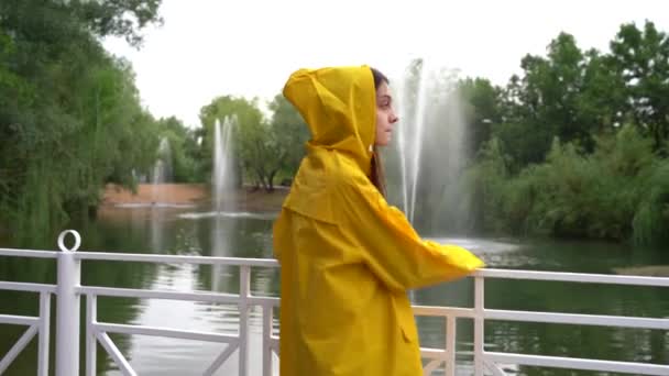 La fille dans l'imperméable jaune se retourne et regarde dans différentes directions. — Video