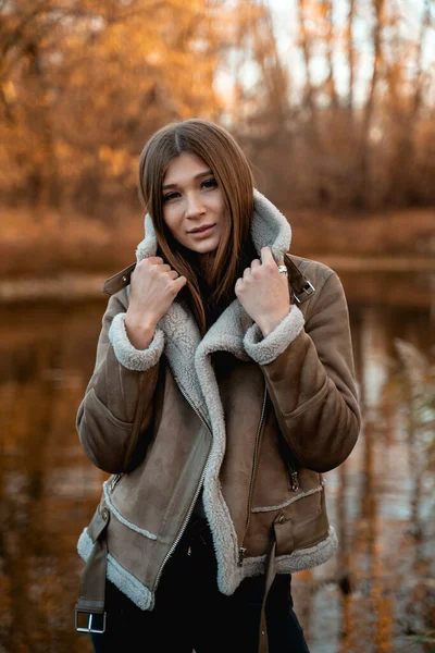 Νεαρή γυναίκα με ζεστό παλτό από δέρμα προβάτου στέκεται στο δάσος του φθινοπώρου — Φωτογραφία Αρχείου