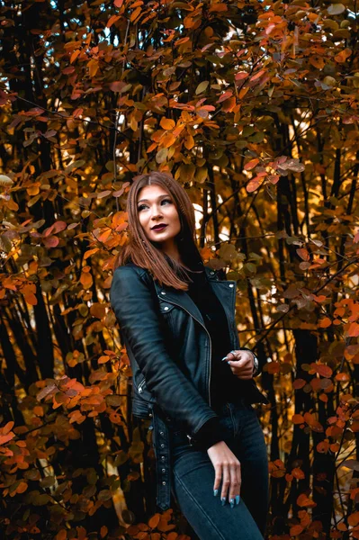 Ładna kobieta w czarnych ubraniach na tle klonowych jesiennych liści — Zdjęcie stockowe