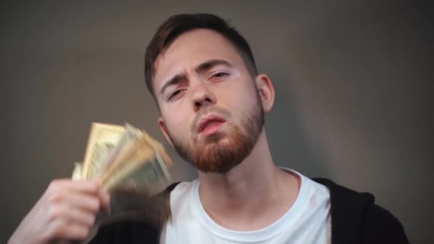 Um jovem exibe um fã de notas de dólar na frente de sua cara — Vídeo de Stock