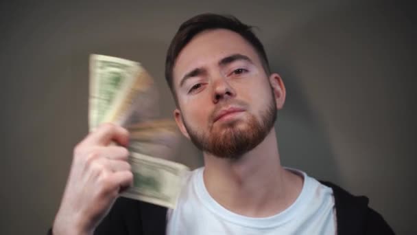 Młody mężczyzna machający przed twarzą fanem banknotów dolarowych — Wideo stockowe