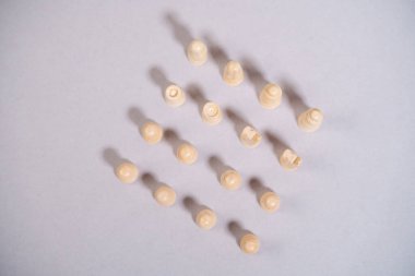 Beyaz satranç taşları gri arkaplanda kare şeklinde duruyor.