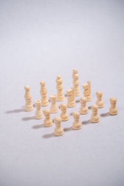 Beyaz satranç taşları gri arkaplanda kare şeklinde duruyor.