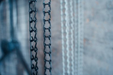 Gri zemin üzerinde asılı demir siyah ve beyaz zincir, yakın plan.