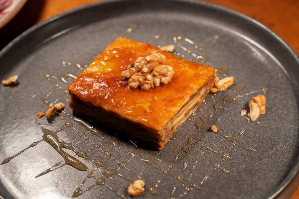 pahlava dessert with honey and walnuts lies on a black plate