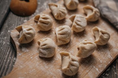 Donmuş, güzel yontulmuş hamur köfteleri un serpiştirilmiş, mutfak malzemeleri, ahşap arka plan.