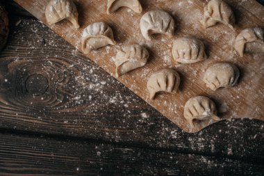 Donmuş, güzel yontulmuş hamur köfteleri un serpiştirilmiş, mutfak malzemeleri, ahşap arka plan.