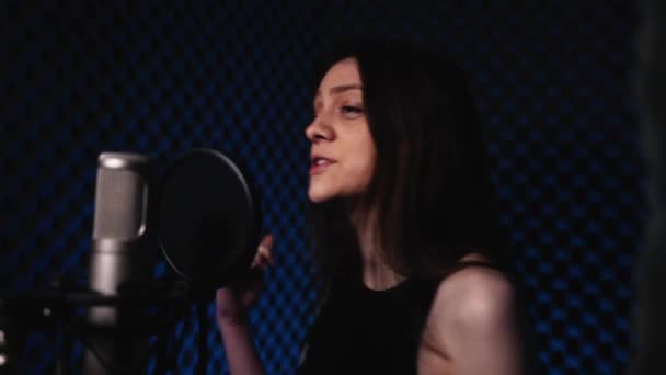 Jeune femme dans un studio d'enregistrement chante une chanson dans un microphone et danse — Video