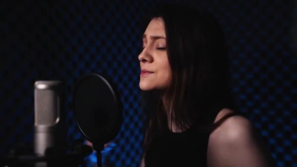 Νεαρή γυναίκα σε στούντιο ηχογράφησης τραγουδάει ένα τραγούδι σε μικρόφωνο και χορεύει — Αρχείο Βίντεο