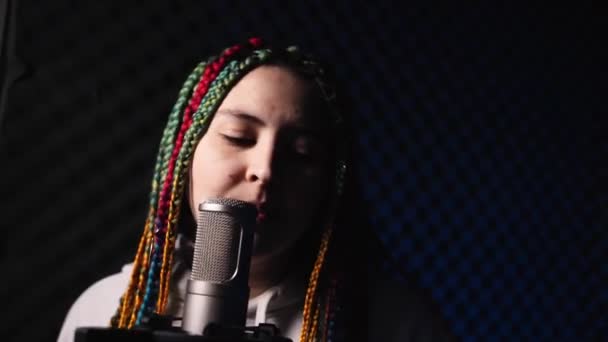 Mujer joven con el pelo de color se para en un estudio de grabación en auriculares — Vídeos de Stock