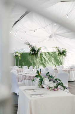 Doğal ve yapay çiçeklerle dekoratif masa dekorasyonu, el yapımı kompozisyonlar, beyaz düğün çadırı.