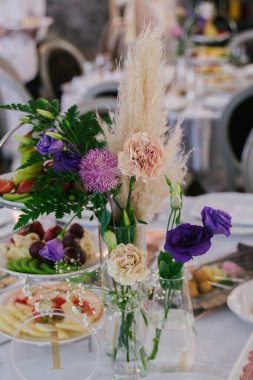 Çiçek aranjmanları, konuk masalarında şeffaf küçük vazolarda, dekorasyonlar.