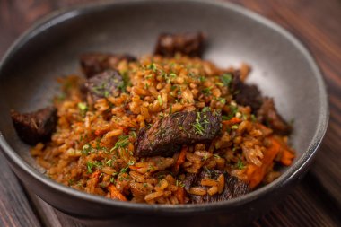 Ahşap arka planda siyah tabakta eti olan geleneksel pilav, menü için fotoğraf