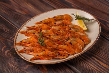 Limon dilimleri ve çeşnili bir tabakta güzelce hazırlanmış kaynamış kaplan karidesleri restoran menüsü için fotoğraf, ahşap arka plan.