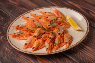 Limon dilimleri ve çeşnili bir tabakta güzelce hazırlanmış kaynamış kaplan karidesleri restoran menüsü için fotoğraf, ahşap arka plan.