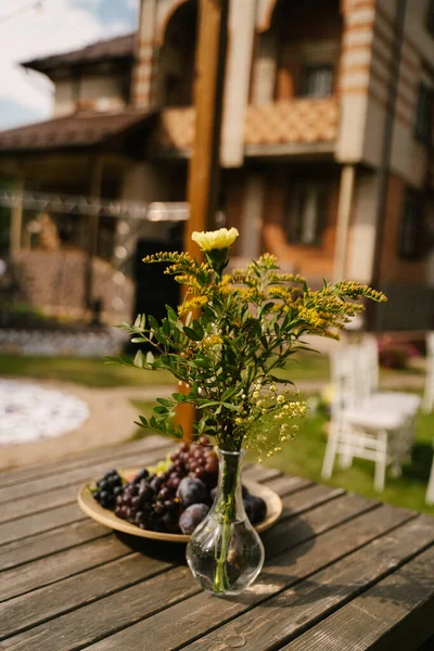 用透明花瓶装饰花卉 并在阁楼木桌上的盘子里放水果 — 图库照片