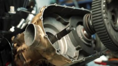 İş eldivenli bir adam ATV için bir CVT kutusu hazırlar.
