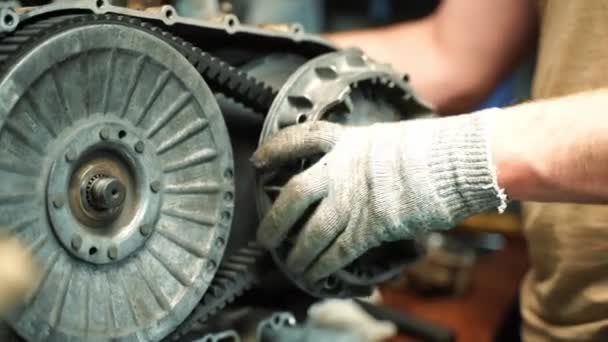 Un homme en gants de travail assemble une boîte CVT pour un VTT, travaux de réparation — Video