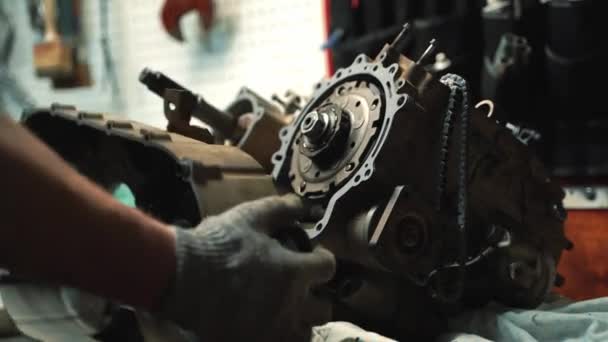Een man met werkhandschoenen installeert een variator box op een ATV motor — Stockvideo