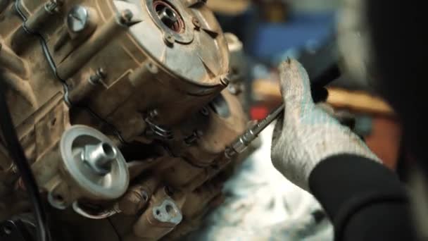 A man locksmith tightens the bolts on the engine cover, repairing an ATV motor — Stock Video