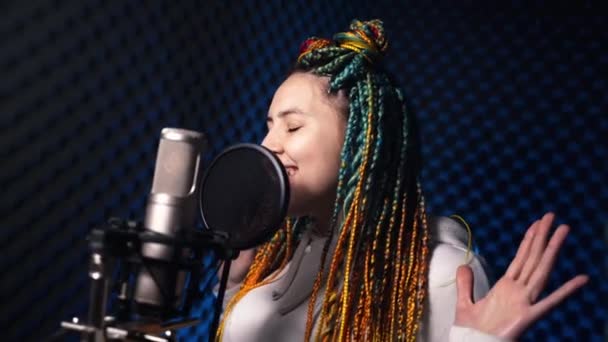 Menina com cabelos coloridos canta uma música ardente em um estúdio de gravação — Vídeo de Stock