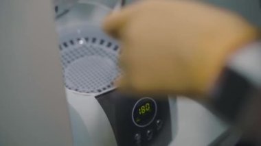 Manikürcü, bakterileri temizlemek için aletleri sterilizatöre koyar.