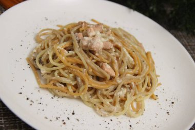 Kırmızı füme balıklı spagetti ve beyaz tabakta beyaz sos.