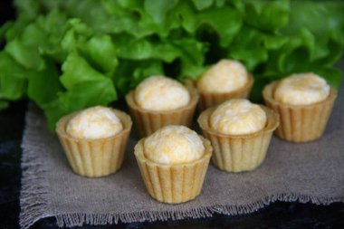 Keten peçete ve arka planda yumurta, peynir ve sarımsaklı atıştırmalık tartlar.