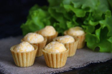 Keten peçete ve arka planda yumurta, peynir ve sarımsaklı atıştırmalık tartlar.