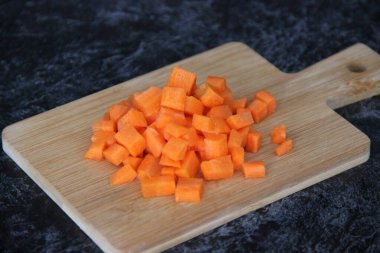 Küçük bir tahta üzerinde küçük küplere kesilmiş taze havuçlar.