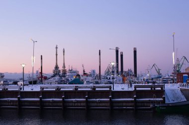 Klaipeda, Litvanya - 14 Ocak 2021. Kar ile kaplı endüstriyel liman yapıları. Soğuk pembe ve mavi gökyüzü.