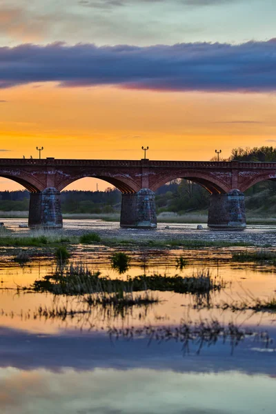 Akşam üzeri Venta nehri üzerindeki tarihi tuğla köprünün manzarası. Fotoğraf Letonya 'da çekildi.