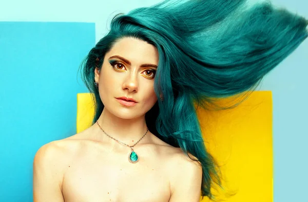 Geometrik arka planda parlak mavi saçlı, genç ve seksi bir kadın. Moda makyajı. Güzel portre..