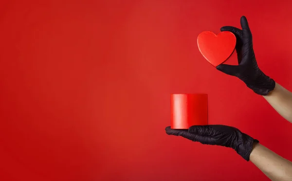 Coronavirus valentines concept. Hands wearing protective latex gloves holding red heart shaped box