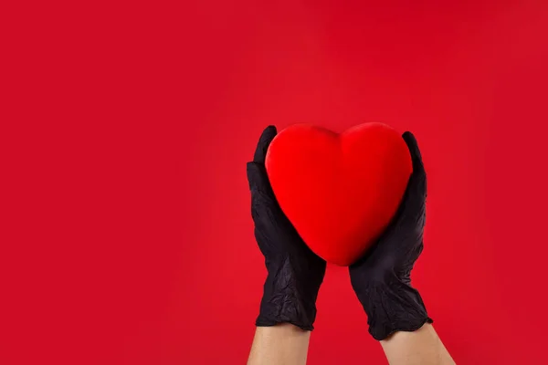 Coronavirus valentines concept. Hands wearing protective latex gloves holding red heart