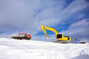 Birkaç turuncu ve sarı sürüngen kazıcı ve bir inşaat alanında duran bir araba. Kiralık, toprak işleri için kiralama.