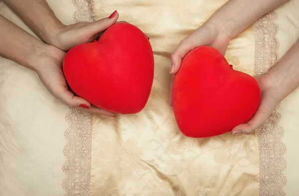 LHBT-konseptet. Kvinners hender holder røde hjerter i sengen. – stockfoto