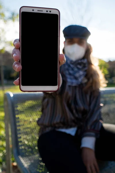 Girl showing the cell phone to the camera.