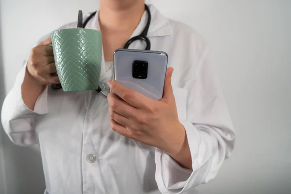 Doktor bir fincan kahve ve cep telefonuyla mola verdi..
