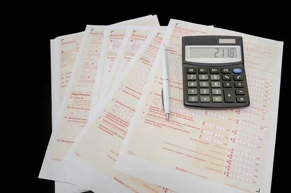 Australian tax forms with pen and calculator on black background. View from above. Tax concept. Financial document. Tax time