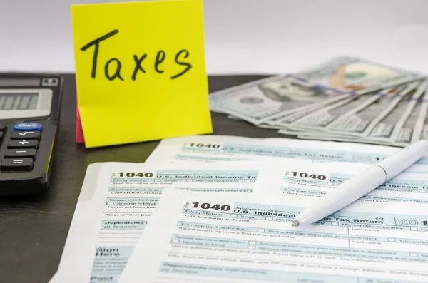 税は黒の木のテーブルの上にドル ステッカー ペンと計算機で1040を形成します 税の時間概念 財務書類 — ストック写真