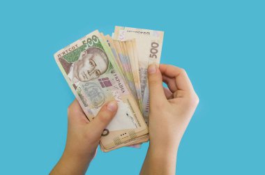 Mavi arka planda izole edilmiş dişi ellerde Ukrayna Hrivnia 'sı. Para yığını. Finansal konsept. Bir sürü 500 Hryvnia banknotu..