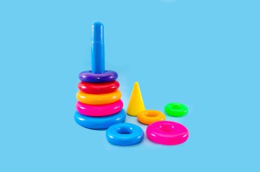 Çocukların çok renkli piramidi mavi arka planda izole edilmiş. Motor becerilerini geliştiren çocuklar için oyuncaklar