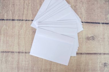 Tahta bir masanın üzerinde bir sürü beyaz boş zarf..