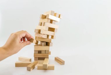 Tahta bloklardan bir kule ve insan eli bir blok alır. Planlama, risk ve iş stratejisi. Kuleden tahta bir blok alma riskini göze alarak..